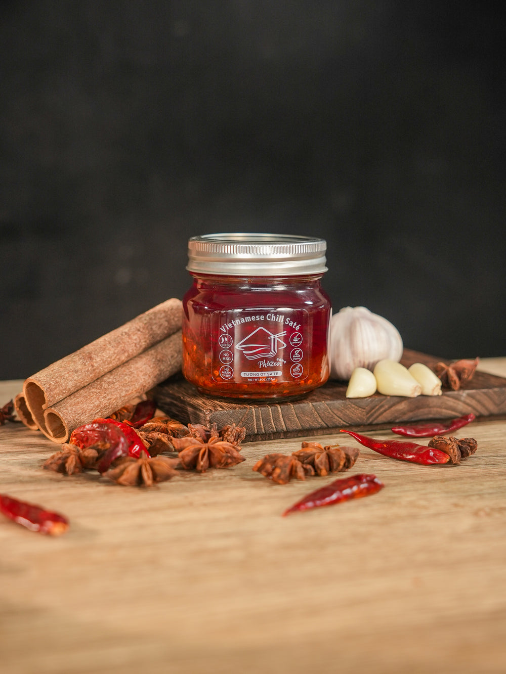 Phởzen Chili Saté jar on top of chopping board with various spices.