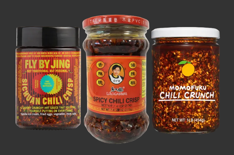 Three jars of spicy chili crisp sauces on a white background