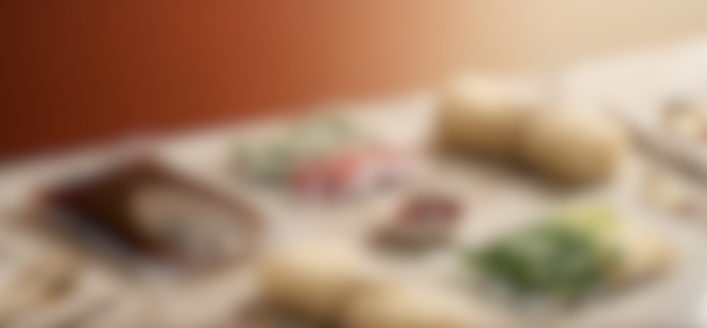 A blurred, atmospheric banner image showing fresh Vietnamese ingredients and spring rolls on a light wooden surface for the Phởzen website.